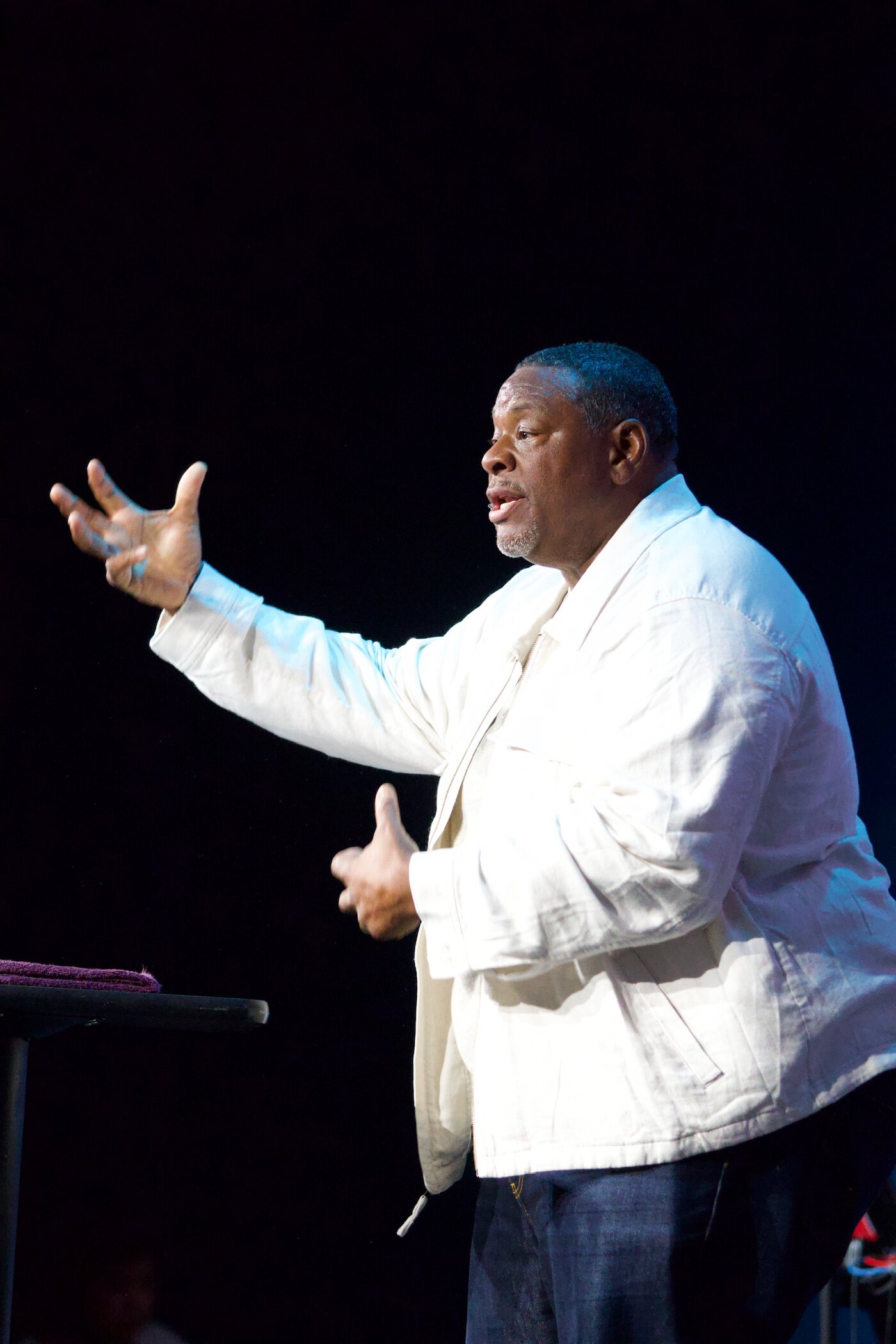 Gino Mingo speaking on stage with an open hand